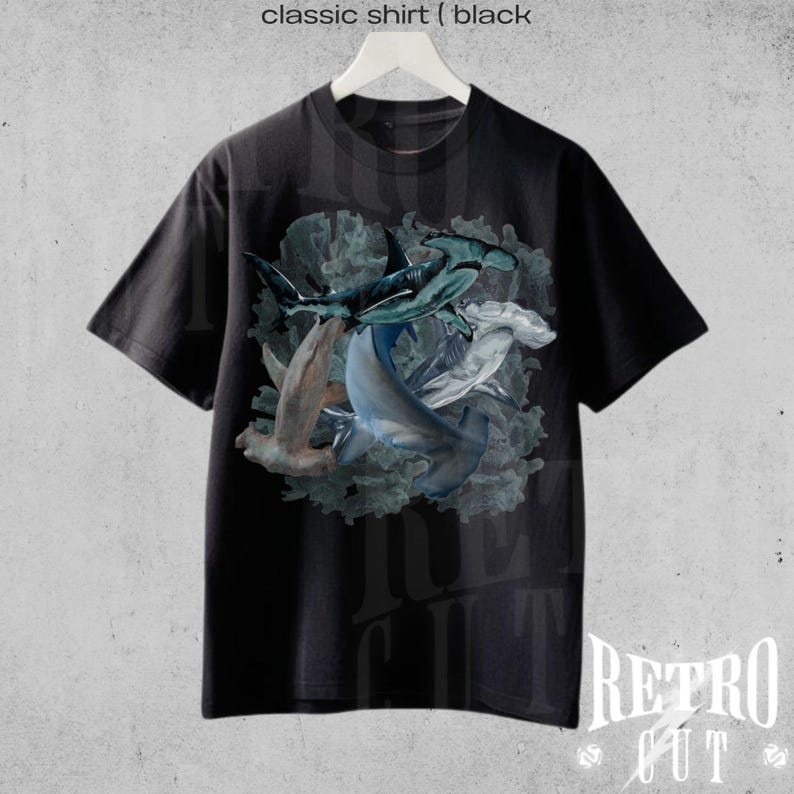 May include: Black t-shirt with a graphic print of hammerhead sharks in a swirling pattern. The sharks are blue, gray, and white. The background is a dark blue with a green and white coral reef.