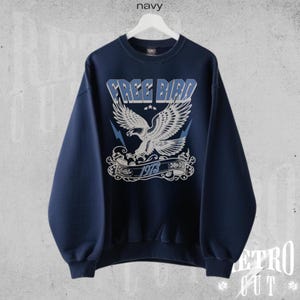 May include: A navy blue sweatshirt with a white eagle graphic and the text "FREE BIRD 1978" printed on the front.