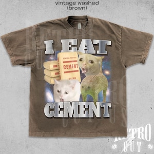 Op de afbeelding: Bruin vintage gewassen t-shirt met een grafisch ontwerp met de tekst "I EAT CEMENT" in zilveren letters. Het ontwerp bevat afbeeldingen van katten en een zak cement.