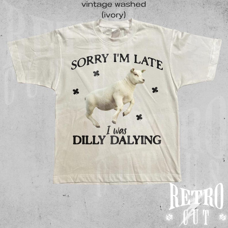 May include: A white t-shirt with a vintage washed look. The shirt features a black graphic of a sheep with the text "SORRY I'M LATE I was DILLY DALYING".
