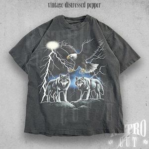 May include: A vintage distressed black t-shirt with a graphic print of two wolves and an eagle with lightning bolts in the background.