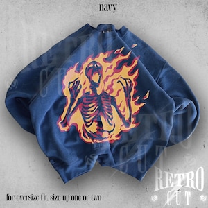 May include: Navy blue sweatshirt with a graphic of a skeleton engulfed in flames. The text "for oversize fit, size up one or two" is printed below the graphic.