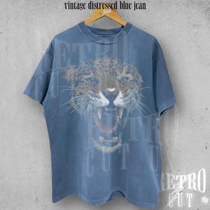 May include: A vintage blue t-shirt with a distressed look featuring a graphic of a snarling jaguar.