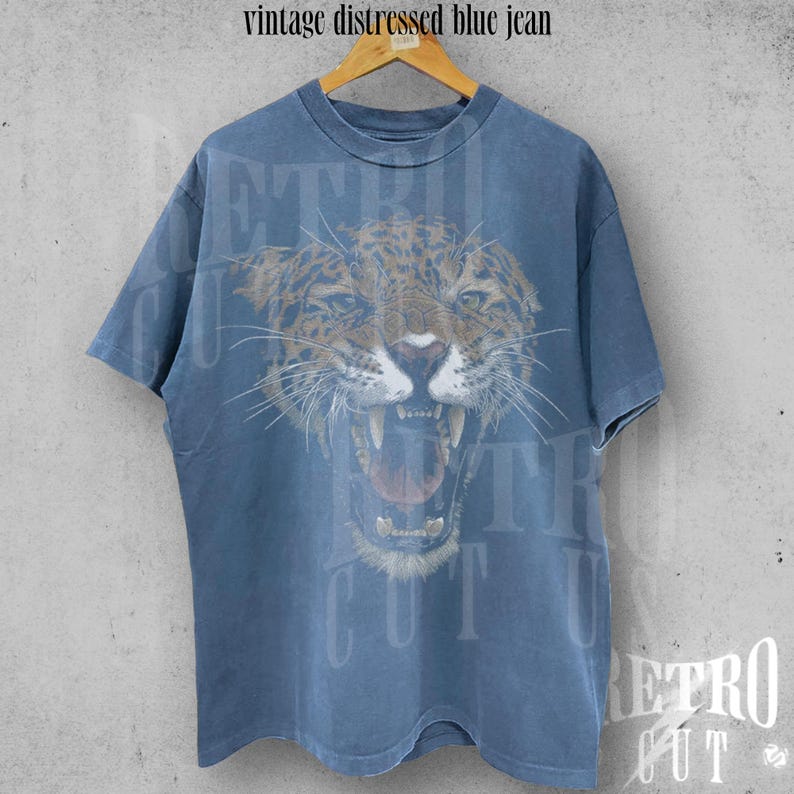 May include: A vintage blue t-shirt with a distressed look featuring a graphic of a snarling jaguar.