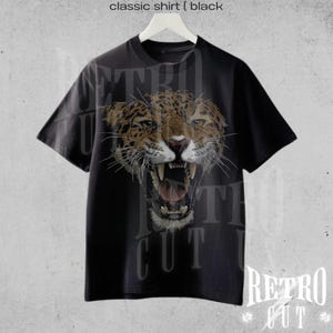 May include: Black t-shirt featuring a graphic of a roaring jaguar's head. The text "Retro Cut" is printed on the shirt.
