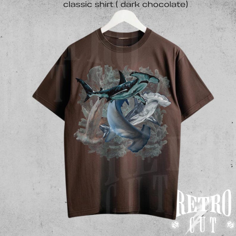 May include: A brown t-shirt with a graphic print of three hammerhead sharks swimming in a coral reef. The text "classic shirt ( dark chocolate )" is printed above the image.