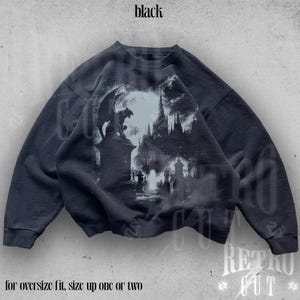 May include: Black sweatshirt with a graphic print of a gothic cathedral and a gargoyle. The text "for oversize fit, size up one or two" is printed below the image.