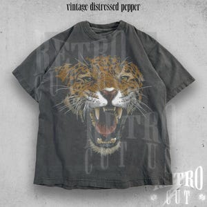 May include: A vintage distressed grey t-shirt featuring a graphic print of a snarling jaguar. The shirt has a faded look and the text "Retro Cut" is visible at the bottom.