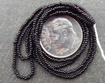 Size 18/0 tiny antique seed beads in opaque black. Late 1800's vintage glass microbeads hank.