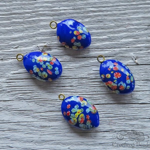 Vintage Japanese millefiori glass pendants in royal blue with multicolor flowers. 15x21 mm oval Tombo glass charms drops w/ gold metal loop.