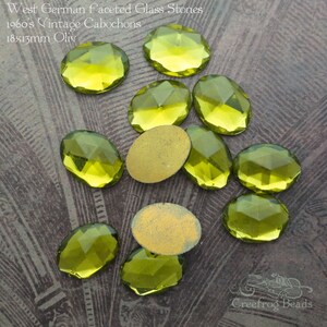 May include: A collection of 10 oval-shaped, faceted glass stones in a light green color. The stones are 18x13mm and are labeled as "West German faceted glass stones 1960's vintage cabochons 18x13mm Oliv".