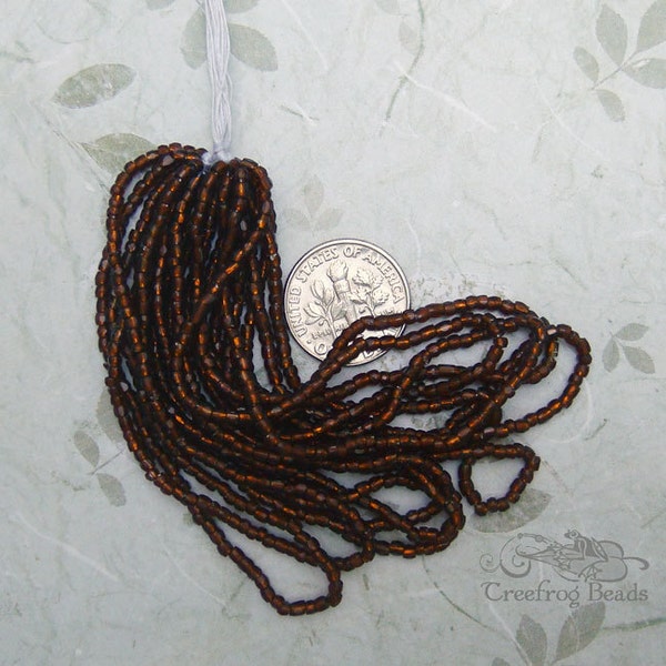 Early 1900's vintage glass seed beads in transparent brown root beer. Mini hank of sparkling silver lined faceted 3 cut beads.