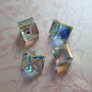 May include: Four iridescent clear glass cube beads with beveled edges. The beads are approximately 1/2 inch in size.