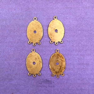 May include: Four gold-toned metal oval-shaped pendant connectors with three loops at the bottom. The connectors have a scalloped edge and a small hole in the center.