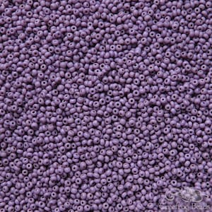 May include: A close-up image of a large quantity of small, round, purple glass beads. The beads are all the same size and shape, and they are arranged in a random pattern.