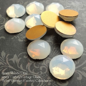 May include: A collection of 13mm white opal cabochons, vintage glass from West Germany. The cabochons are faceted and have a milky white color with a slight iridescent sheen.