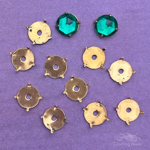 May include: Ten gold-toned metal settings with four prongs each, and two green glass cabochons. The settings are designed to hold gemstones or other embellishments.