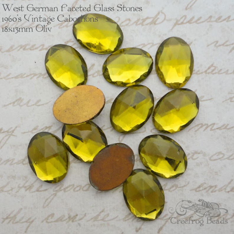 May include: A collection of 10 oval-shaped, faceted glass stones in a yellow-green color. The stones are 18mm x 13mm and are labeled as "West German faceted Glass Stones 1960's Vintage Cabochons 18x13mm Oliv".