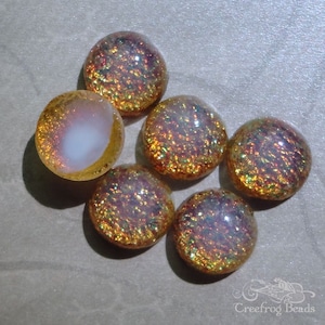 May include: Six iridescent glass cabochons in shades of gold, pink, and white. The cabochons have a textured surface and are perfect for jewelry making.