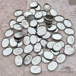 Könnte beinhalten: Eine große Gruppe von silbernen ovalen Metallelementen mit einem gewellten Rand. Die Elemente sind auf einem hellbraunen Hintergrund verstreut.