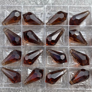 May include: A close-up view of 16 brown glass teardrop-shaped beads arranged in a clear plastic packaging. The beads are faceted and have a shiny finish.