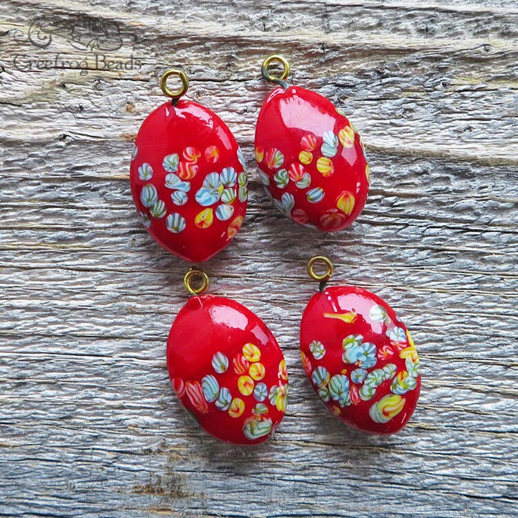 4 Vintage Japanese Tombo glass pendants with millefiori flower design on bright red. 15x21 mm puffy oval drops or charms w/ gold toned loop.