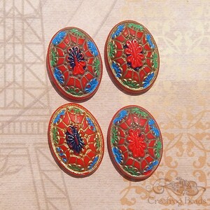 May include: Four oval-shaped glass buttons with a red, blue, green and gold geometric design. The buttons have a raised, textured centre with a floral pattern.