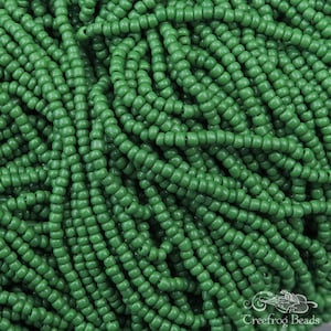 May include: A close-up image of a large quantity of small, round, green beads. The beads are arranged in a random pattern, creating a textured surface.