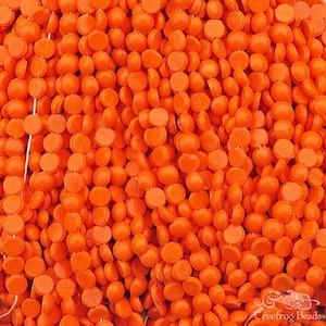 May include: A strand of bright orange round beads. The beads are smooth and have a slightly domed shape.