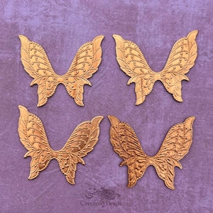 Puede incluir: Cuatro alas de mariposa de metal de color dorado con un diseño detallado. Las alas miden aproximadamente 7,5 cm de ancho y 5 cm de alto.