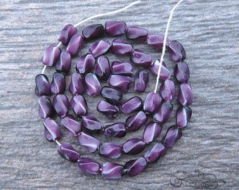 50 vintage pressed glass beads in variegated purple and white satin. Strand of 4x6 mm twisted oval rice shaped beads, made in Czechoslovakia