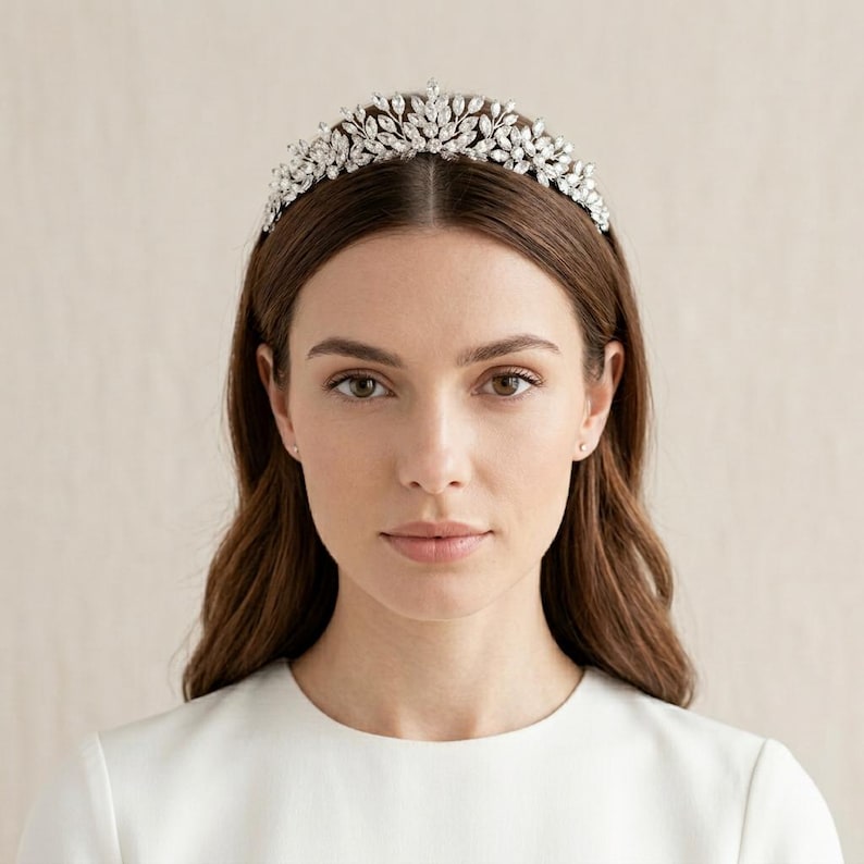 Elegant crystal bridal tiara with leaf-shaped rhinestones on silver headband. Sparkling wedding crown headpiece shown close-up, styled on bride hairstyle and displayed as bridal hair accessory for weddings.