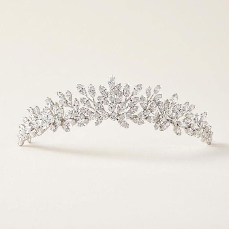 Elegant crystal bridal tiara with leaf-shaped rhinestones on silver headband. Sparkling wedding crown headpiece shown close-up, styled on bride hairstyle and displayed as bridal hair accessory for weddings.