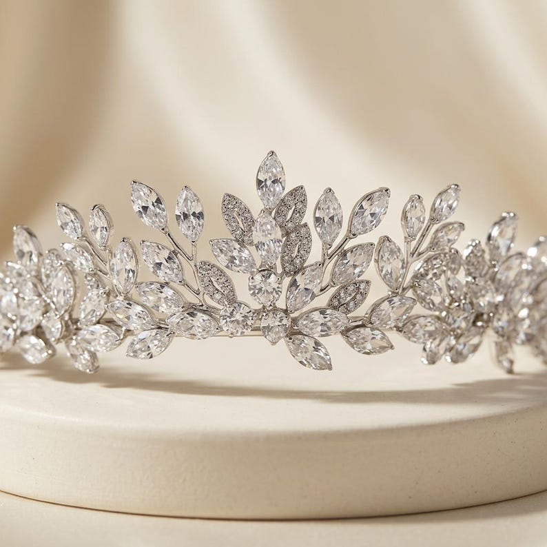 Elegant crystal bridal tiara with leaf-shaped rhinestones on silver headband. Sparkling wedding crown headpiece shown close-up, styled on bride hairstyle and displayed as bridal hair accessory for weddings.