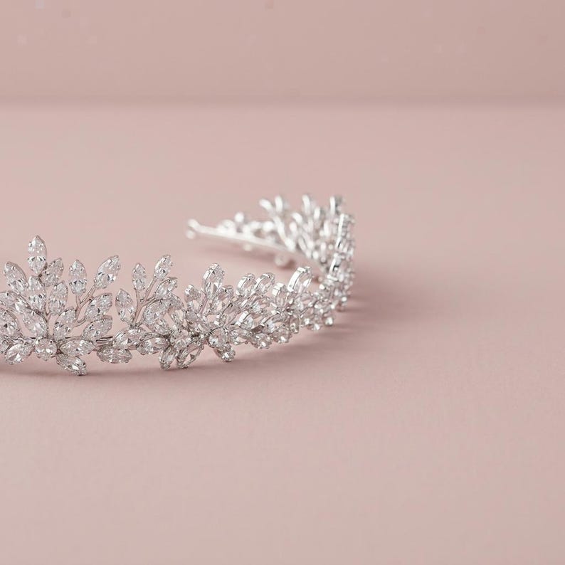 Elegant crystal bridal tiara with leaf-shaped rhinestones on silver headband. Sparkling wedding crown headpiece shown close-up, styled on bride hairstyle and displayed as bridal hair accessory for weddings.