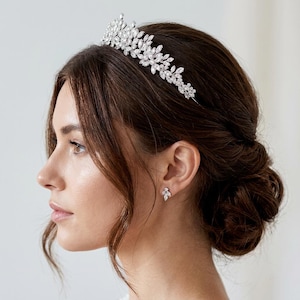 Elegant crystal bridal tiara with leaf-shaped rhinestones on silver headband. Sparkling wedding crown headpiece shown close-up, styled on bride hairstyle and displayed as bridal hair accessory for weddings.