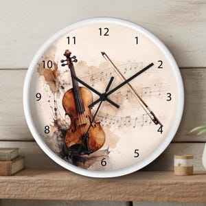 May include: A round wall clock with a white frame featuring a watercolor illustration of a brown violin and a bow set against a background of musical notation. The clock face displays black numbers from 1 to 12 and black hour, minute, and second hands.