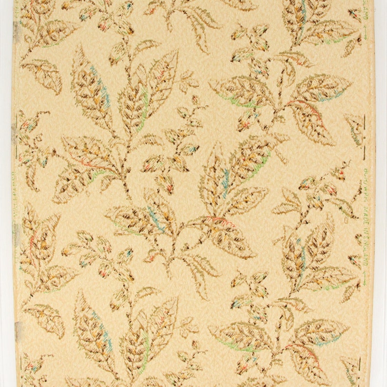 May include: Vintage wallpaper with a repeating pattern of brown, green, and blue leaves on a cream background. The wallpaper has a textured surface and is made in England.