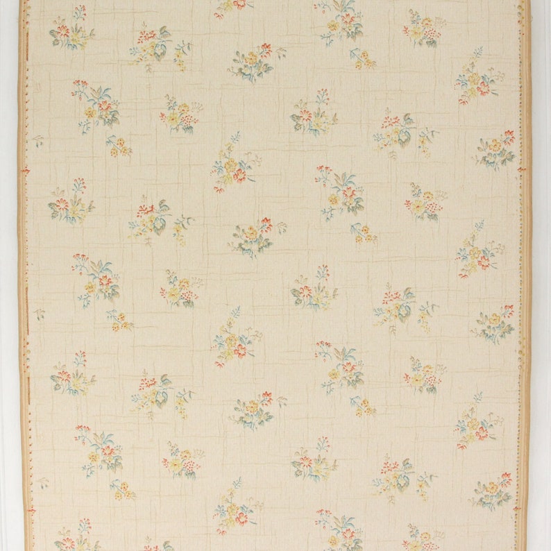 Puede incluir: Un papel tapiz vintage con un delicado patr&oacute;n floral. El papel tapiz presenta peque&ntilde;as flores multicolores sobre un fondo crema con un sutil patr&oacute;n de cuadr&iacute;cula.