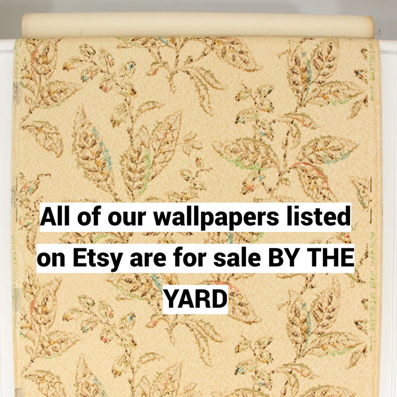 May include: A close-up of a roll of beige wallpaper with a repeating pattern of brown, green, and orange leaves. The text "All of our wallpapers listed on Etsy are for sale BY THE YARD" is printed on the wallpaper.