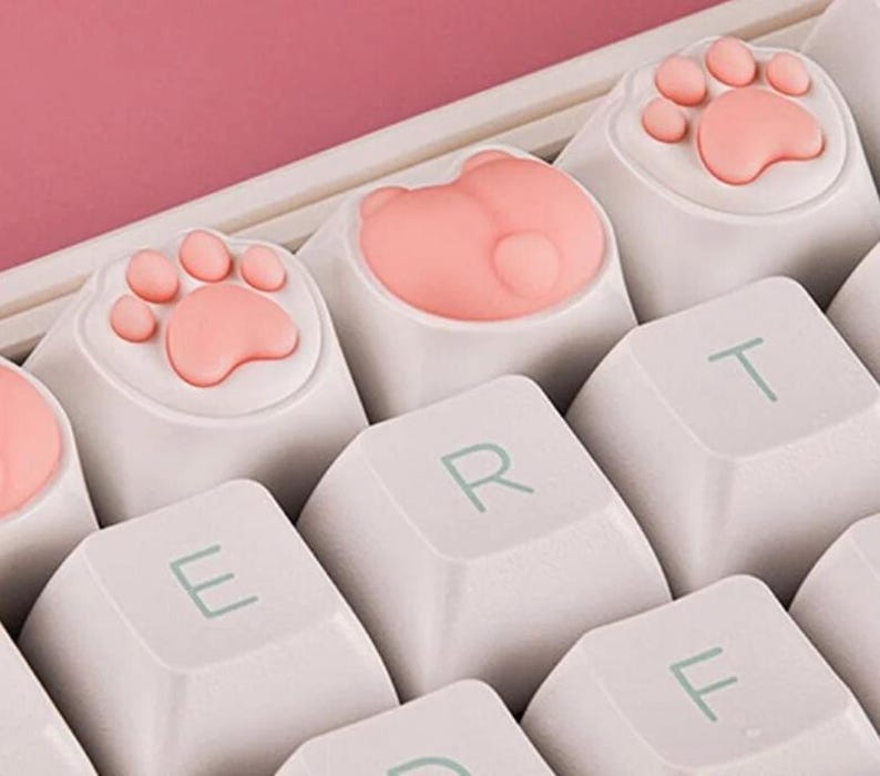May include: A white keyboard with pink paw print and heart-shaped keycaps. The keys are labeled E, R, T, and F.