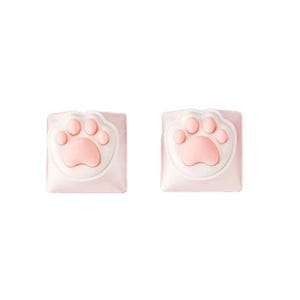 May include: Two pink keycaps with a white border and a raised pink paw print design.