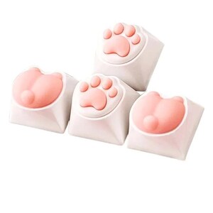 May include: Four white keycaps with pink paw print and paw designs. The keycaps are for a mechanical keyboard.