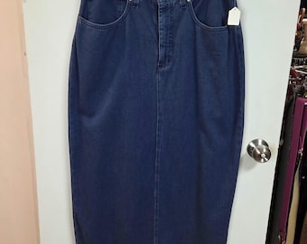 Può includere: Una gonna di jeans blu scuro appesa a una gruccia nera. La gonna ha un classico design a cinque tasche, una chiusura con bottone e cerniera e una piccola etichetta in tasca. La gonna è lunga fino al ginocchio.