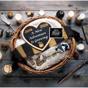 May include: A heart-shaped chalkboard with the text "June 2026 A New Adventure Is Growing" is in a woven basket with a scarf, plush badger, and ultrasound image. Candles, a wand, and decorative items are on a wooden surface.