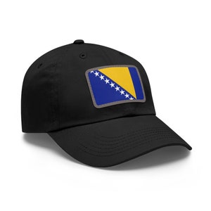 May include: Black baseball cap featuring a rectangular patch with the flag of Bosnia and Herzegovina. The flag design includes a yellow triangle, blue background, and white stars. The cap has a curved brim and a button on top.