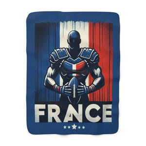 Puede incluir: Una manta azul con una ilustración estilizada de un jugador de fútbol americano con los colores de la bandera francesa. La palabra "FRANCE" está impresa en blanco en la parte inferior, con cinco estrellas debajo.