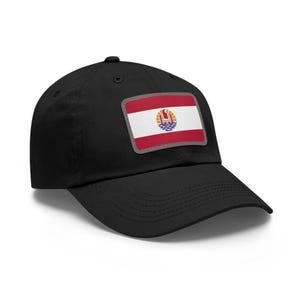 May include: Black baseball cap featuring a rectangular patch with the flag of French Polynesia. The flag design includes red, white, and blue colors with a central emblem. The cap has a curved brim and a button on top.