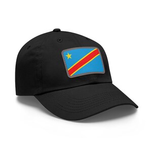 May include: Black baseball cap featuring a patch with the flag of the Democratic Republic of the Congo. The flag patch is rectangular with a blue background, a yellow star, and a red stripe. The cap has a curved brim.