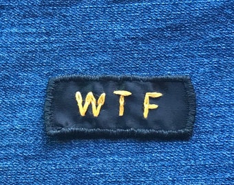 WTF-patch! - Handgemaakte, geborduurde naaipatch. Aangepast naamplaatje. Geel guldenroedeborduurwerk op zwart lint.